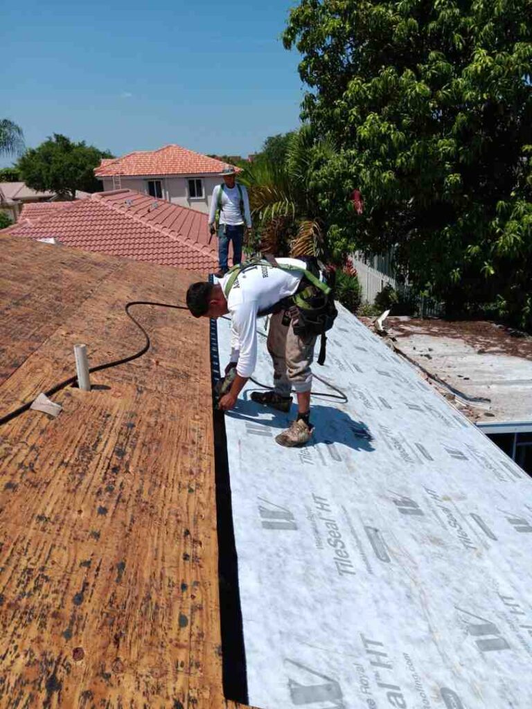 High-quality image showing roofers installing underlayment during roofing repair in a residential neighborhood.