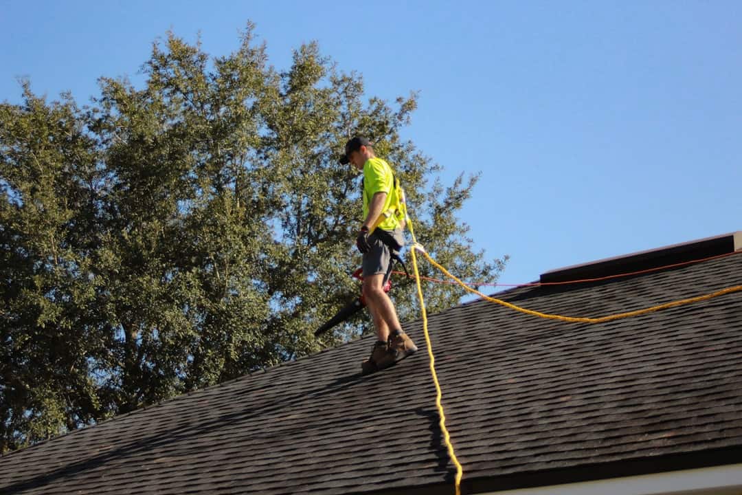 High-angle shot of a roofing professional inspecting a home roof in sunny weather.