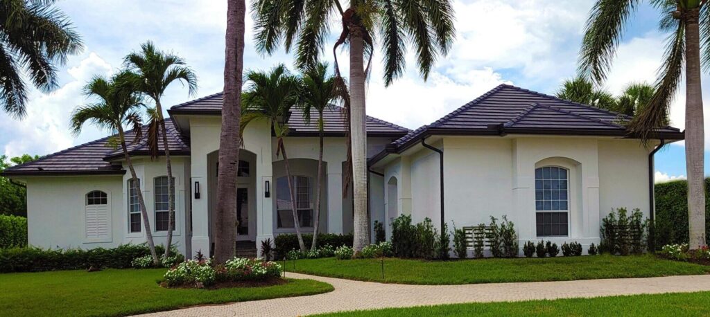 White residential house surrounded by lush palm trees in a tropical setting.